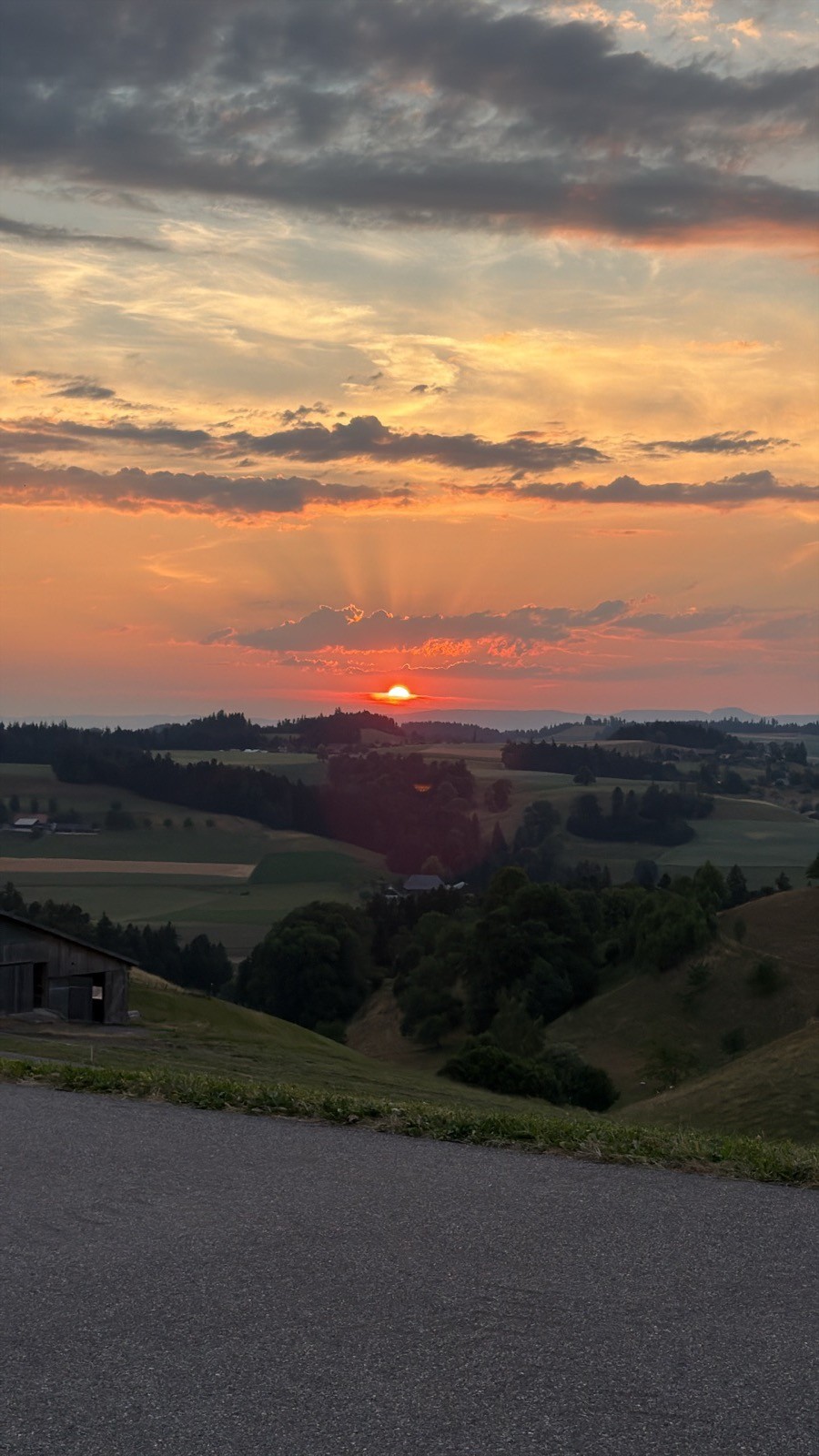 Sonnenuntergang mit Strahlen über den Emmentaler Hügeln