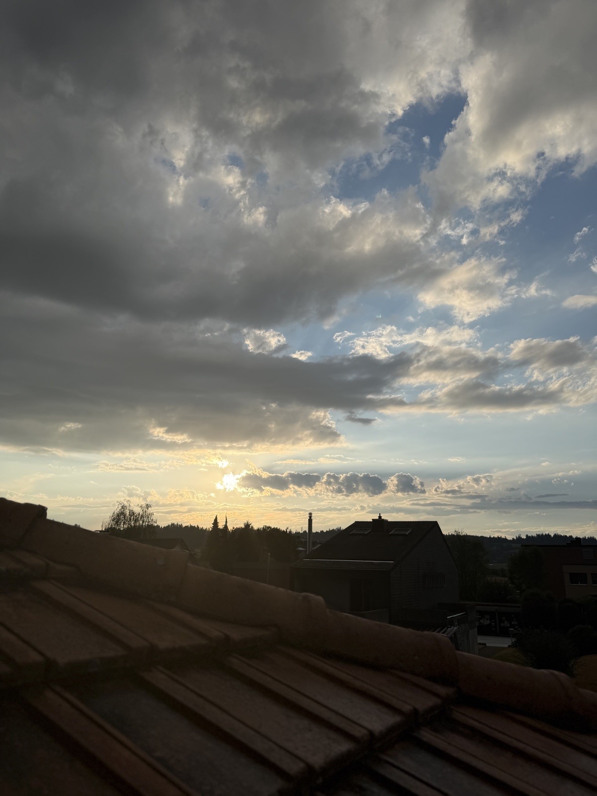 Sonne hinter Wolken über den Dächern von Sumiswald